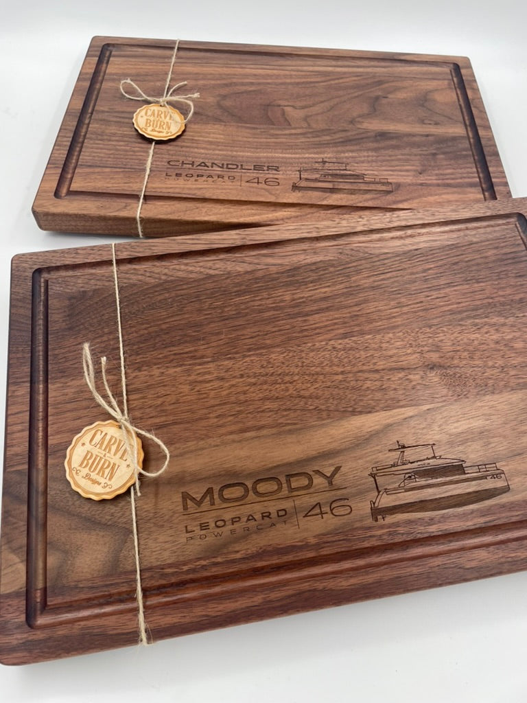 Two black walnut cutting boards engraved with family names, wrapped as gifts