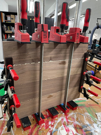 Black walnut boards clamped during glue-up for a 20 inch round serving board