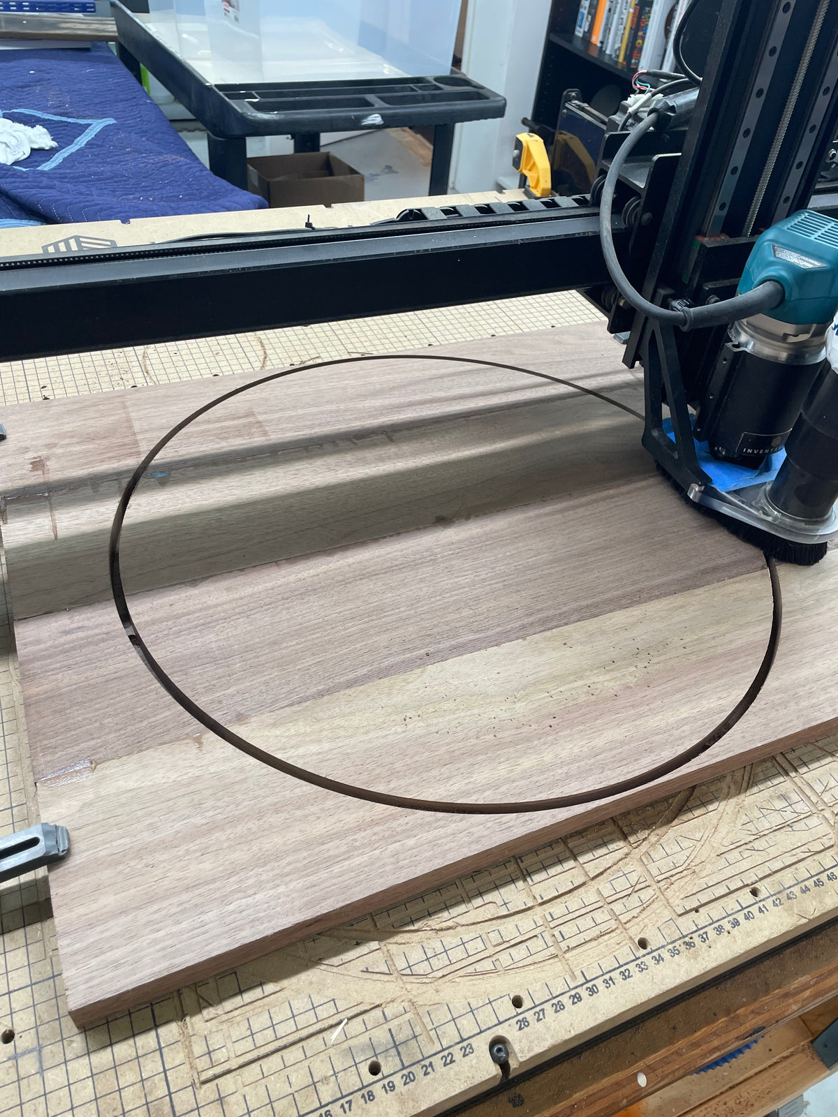 CNC machine cutting a 20 inch circle from a black walnut panel