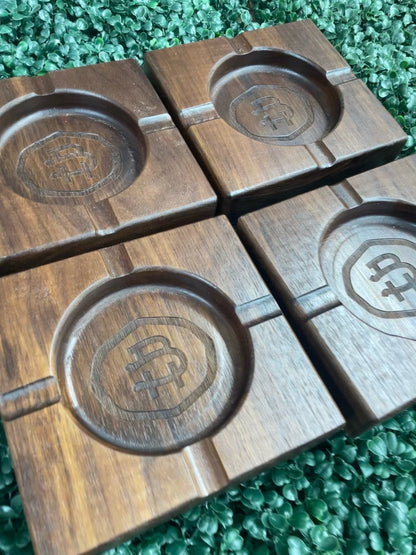 Four black walnut cigar ashtrays arranged together, engraved with initials