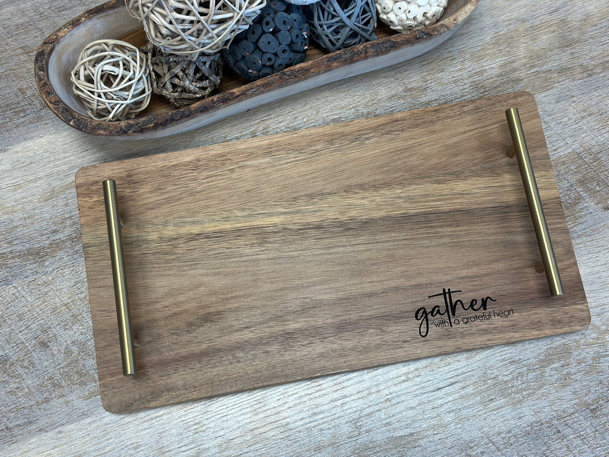 Engraved acacia serving tray with gold handles on a table