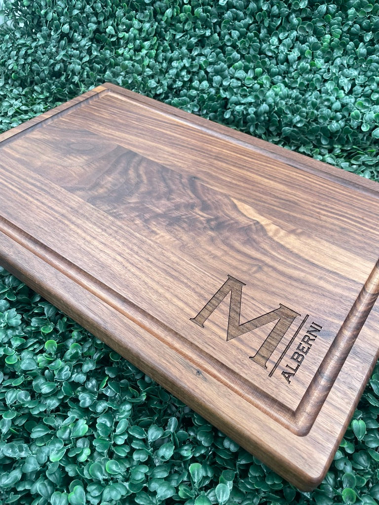 Black walnut cutting board engraved with a large M monogram and family name