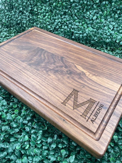 Black walnut cutting board engraved with a large M monogram and family name