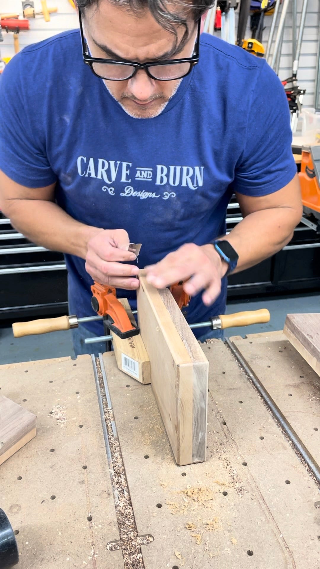 Carve & Burn maker in a branded T-shirt sanding a wood piece in the workshop