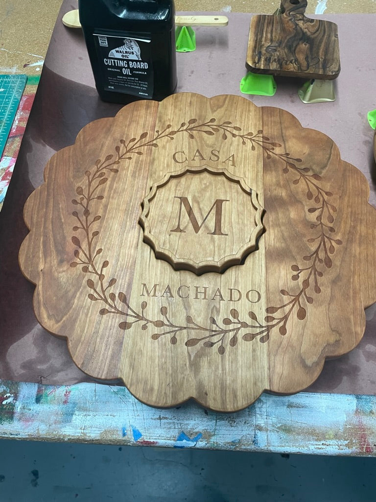 Cherry clamshell board engraved with an M monogram wreath, angled view