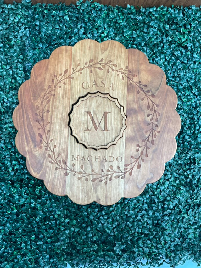 Cherry clamshell charcuterie board engraved with the Casa Machado monogram on greenery