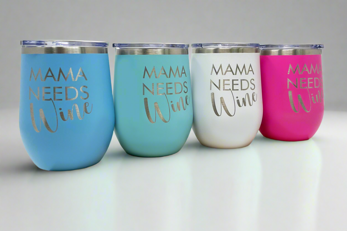 'Mama Needs Wine' 12 oz stemless wine tumbler displayed on a wood block