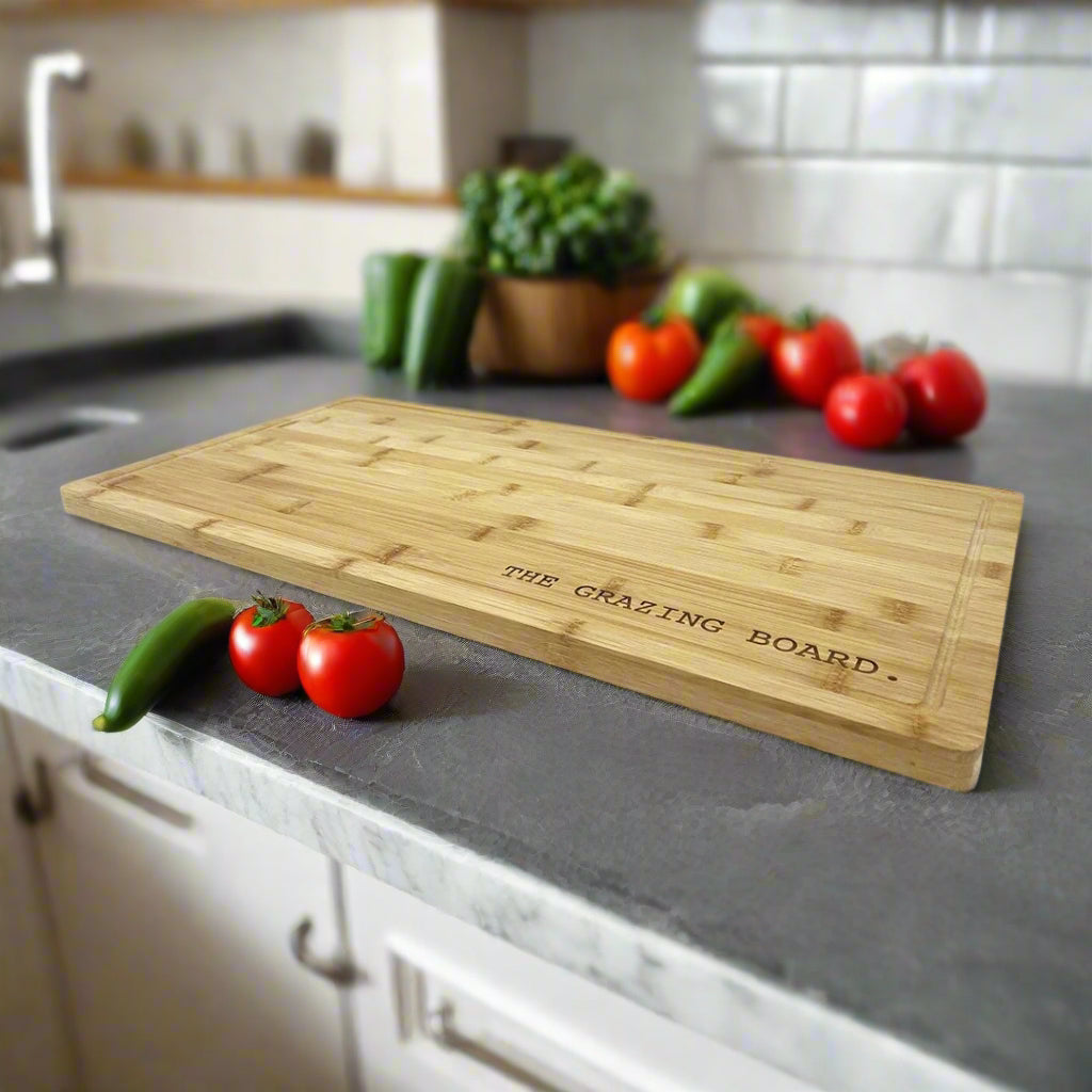 The Grazing Board large bamboo serving board engraved with a name, styled in a kitchen with tomatoes